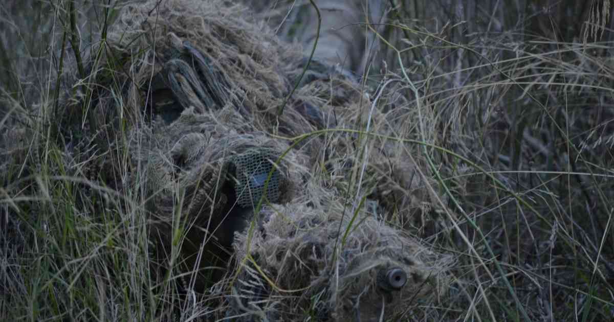 a sniper hidden on the grass